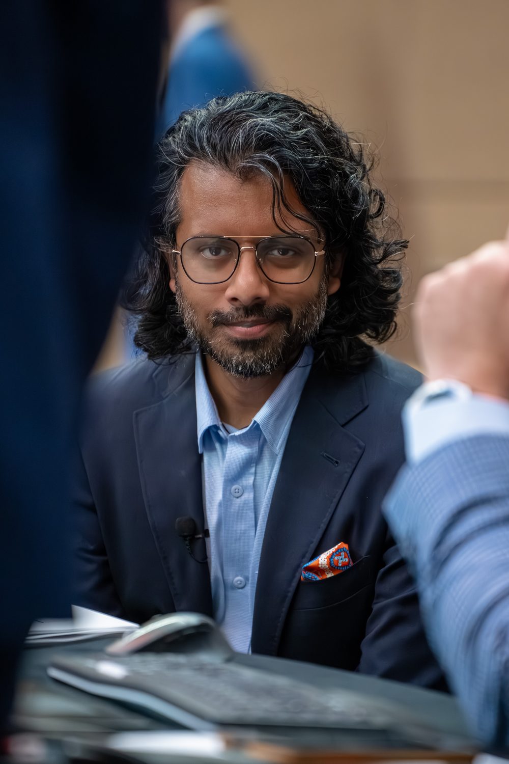 Portrait of the speaker with a patterned pocket square between sessions