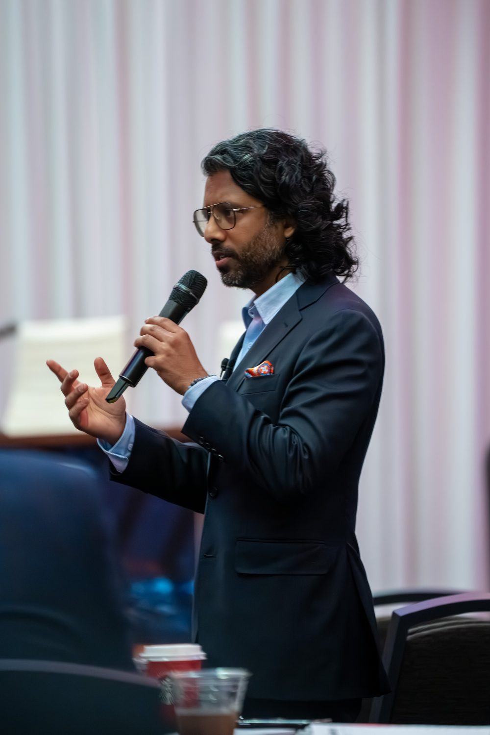 Full-length view of the speaker gesturing while presenting on stage