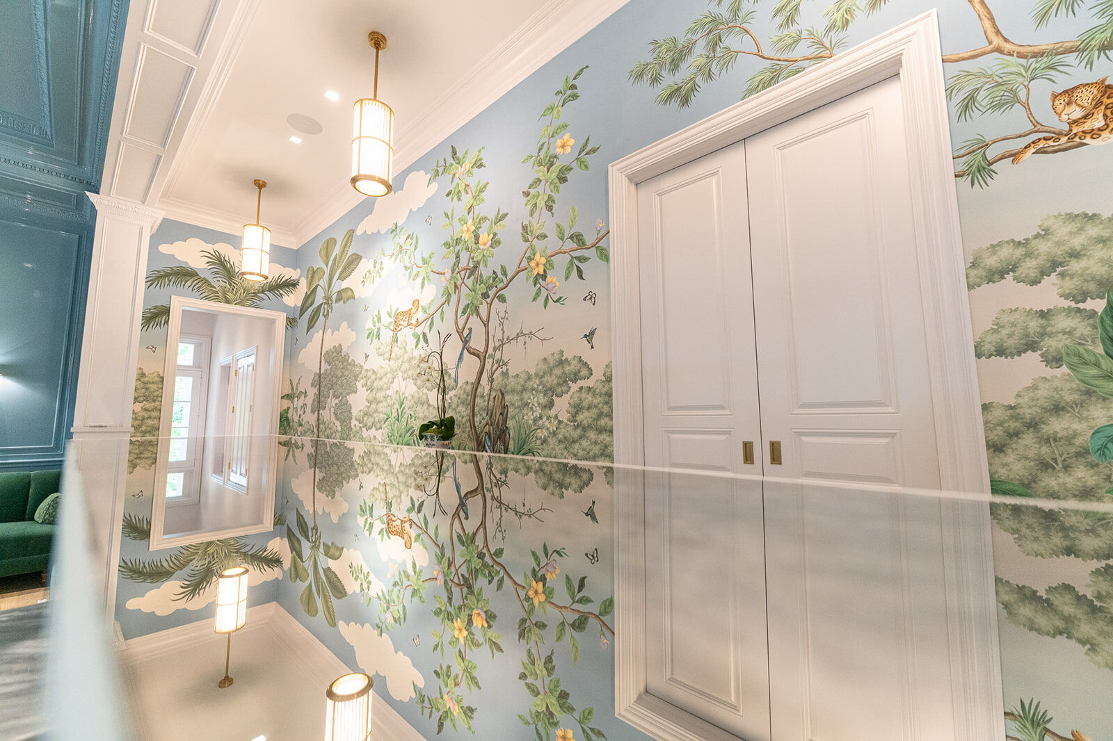 Corridor framed by a jungle mural and a paneled door
