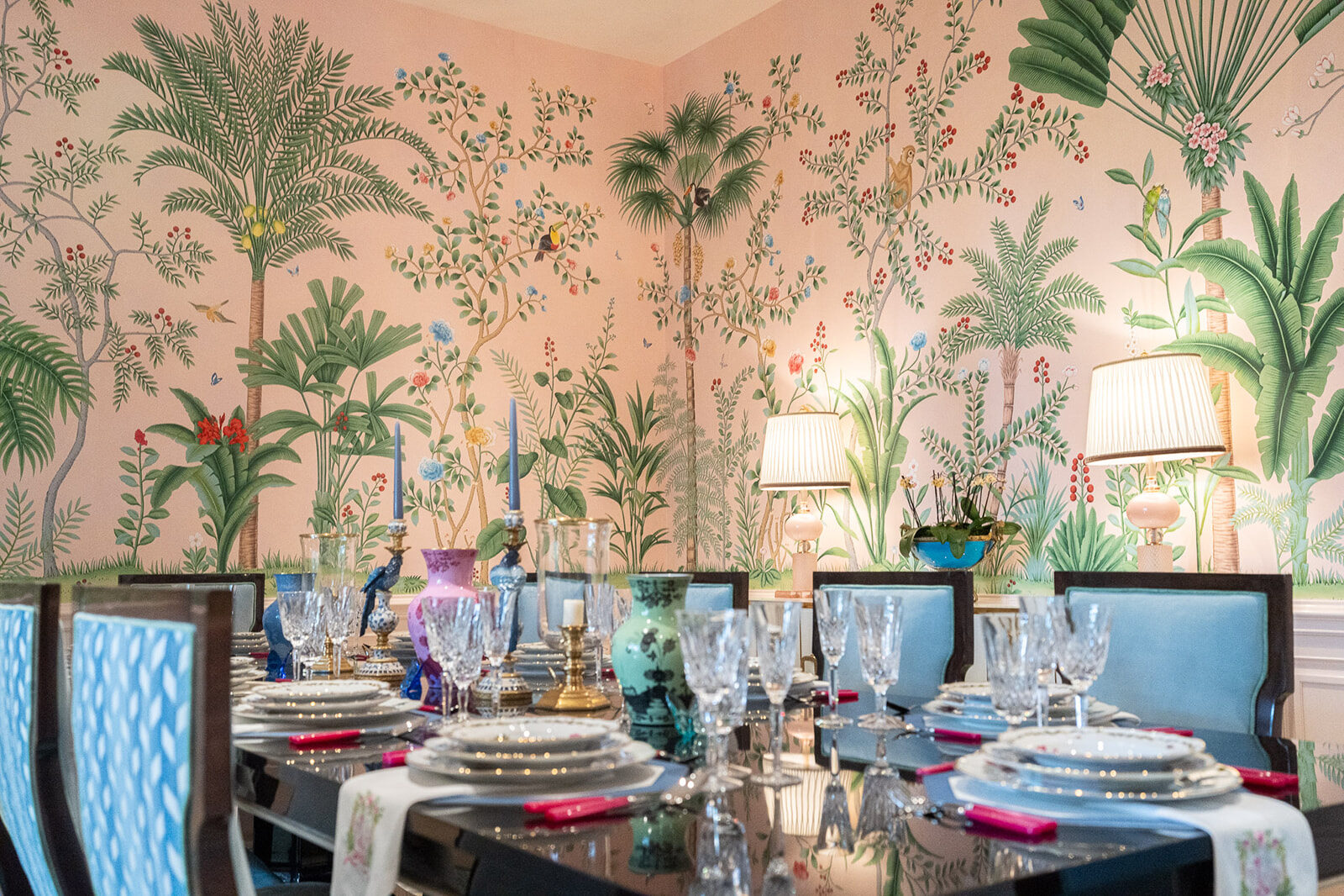 Crystal and porcelain place settings against a palm-motif mural