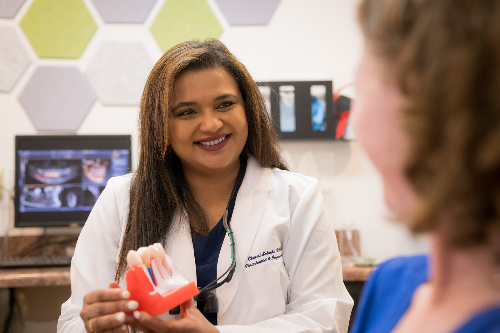 Periodontist explaining treatment with a dental model to a patient