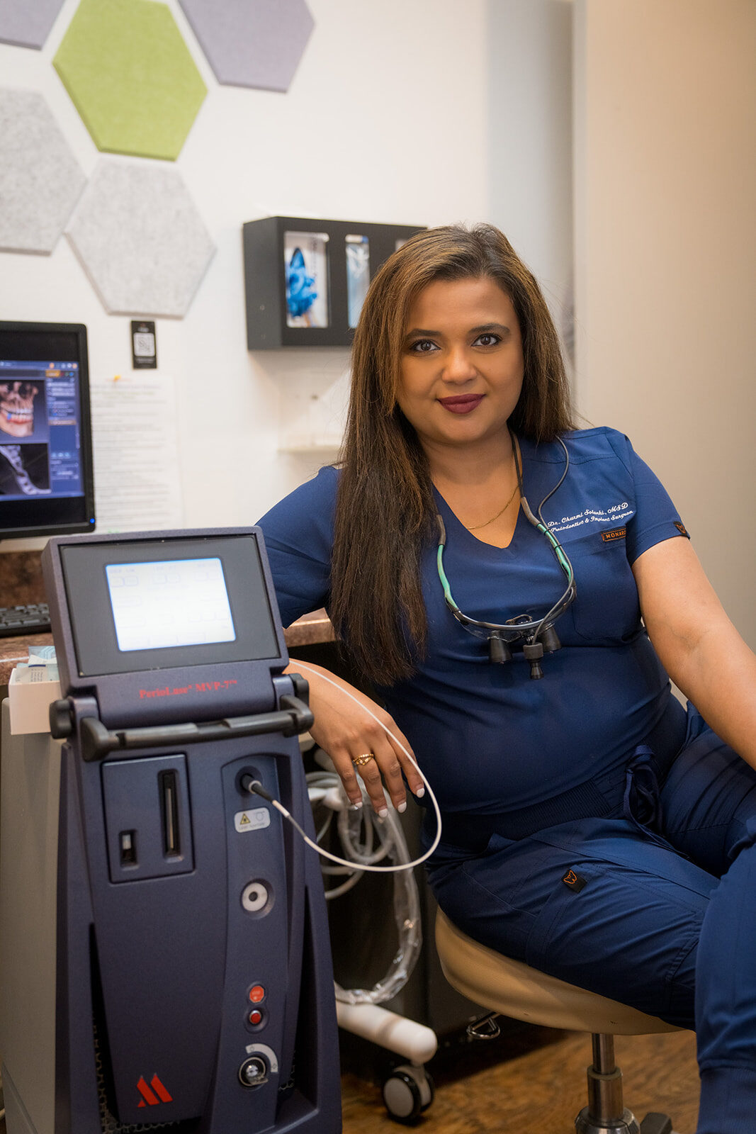 Periodontist seated beside a dental laser system