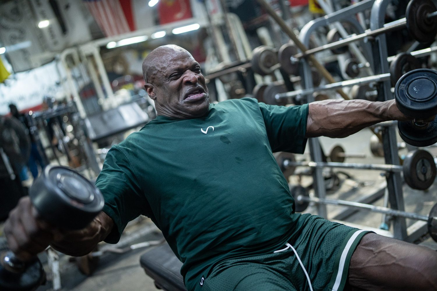 Ronnie Coleman straining through a seated dumbbell lateral raise