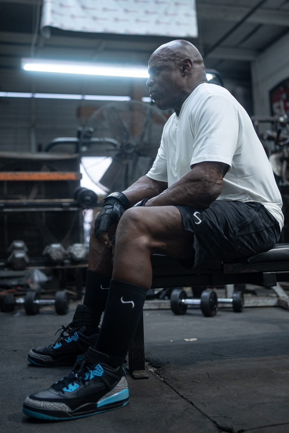 Ronnie Coleman resting on a bench in a warehouse gym