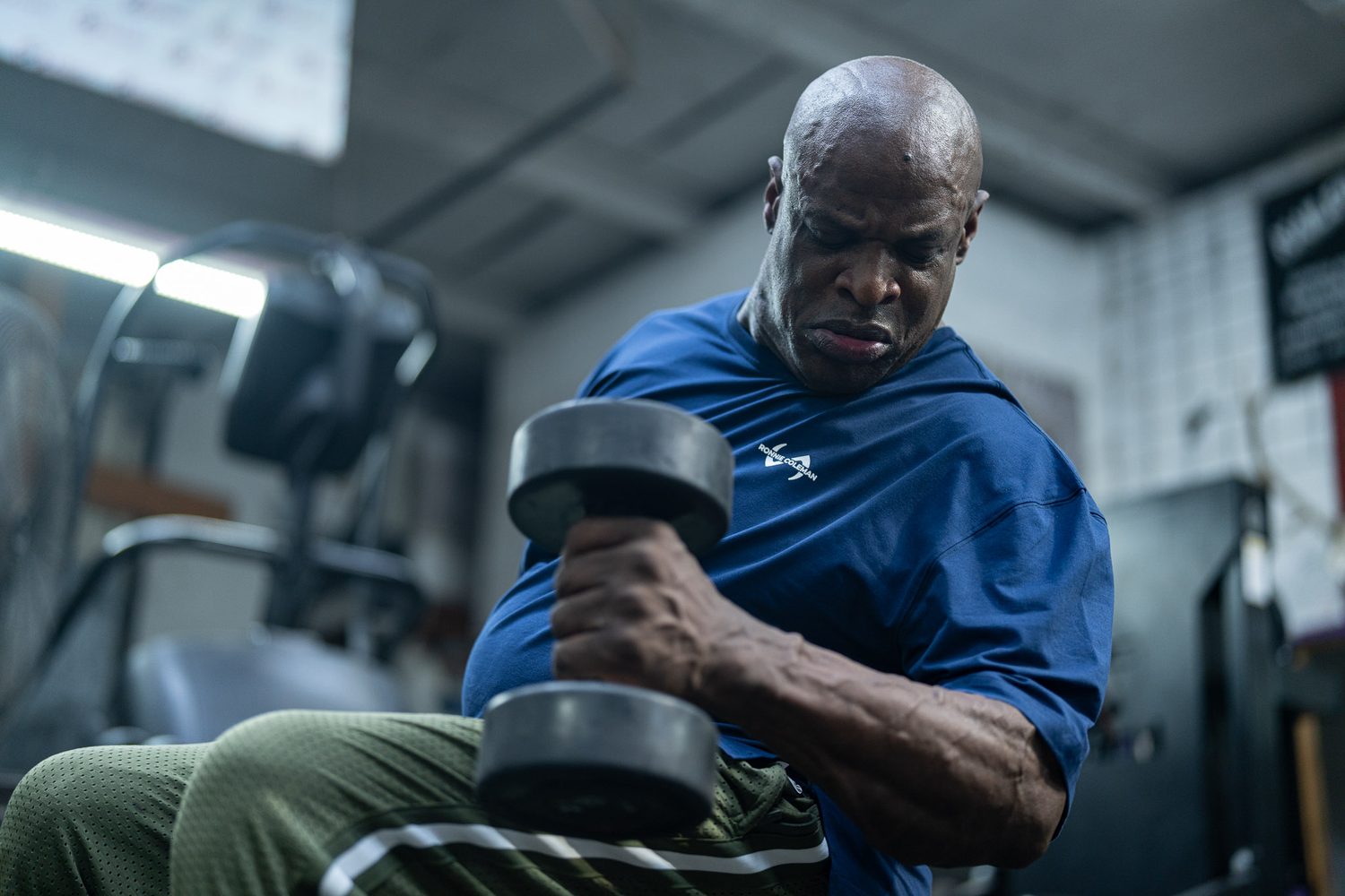 Ronnie Coleman curling a dumbbell in a Ronnie Coleman signature tee
