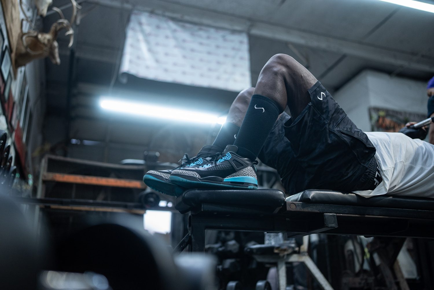 Low-angle detail of training sneakers and socks on a gym bench
