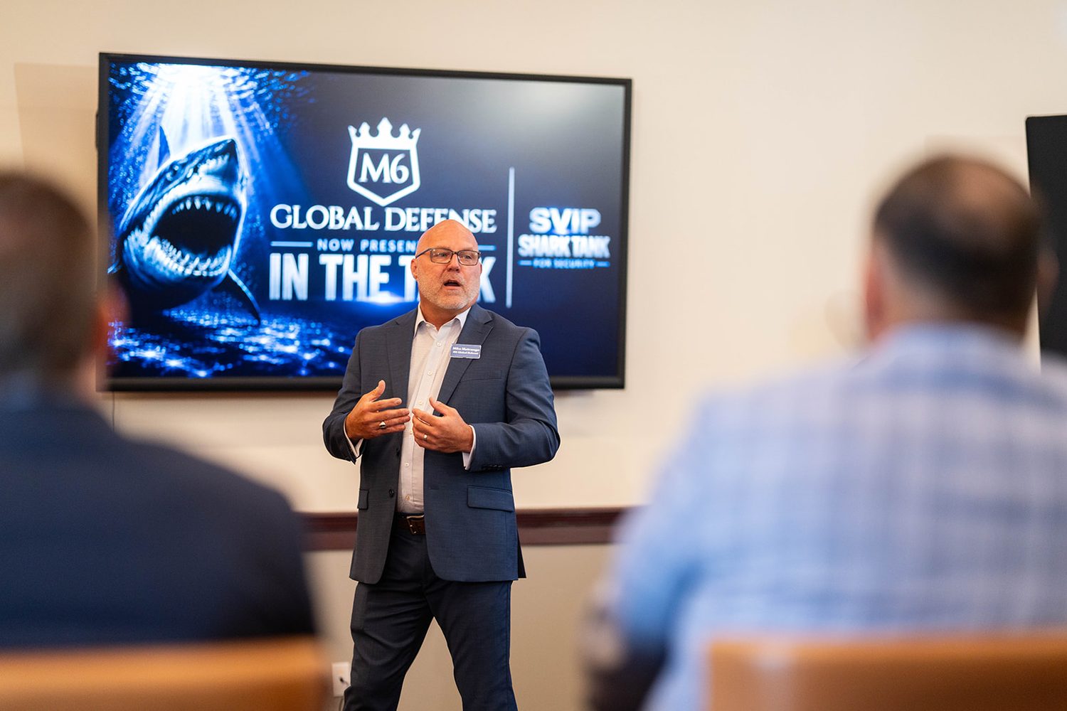 Presenter delivering a pitch beside a Global Defense title slide