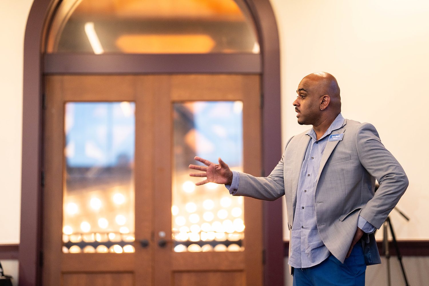 Speaker gesturing mid-pitch near the venue's arched doors