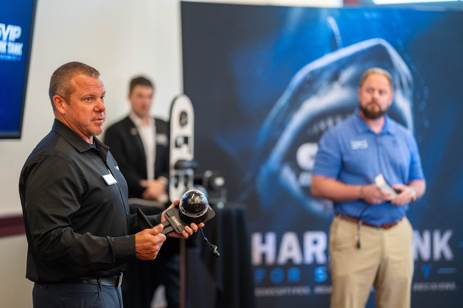 Presenter showing a security camera during a product pitch
